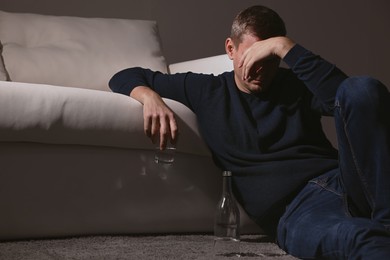Photo of Addicted drunk man with alcoholic drink near sofa indoors