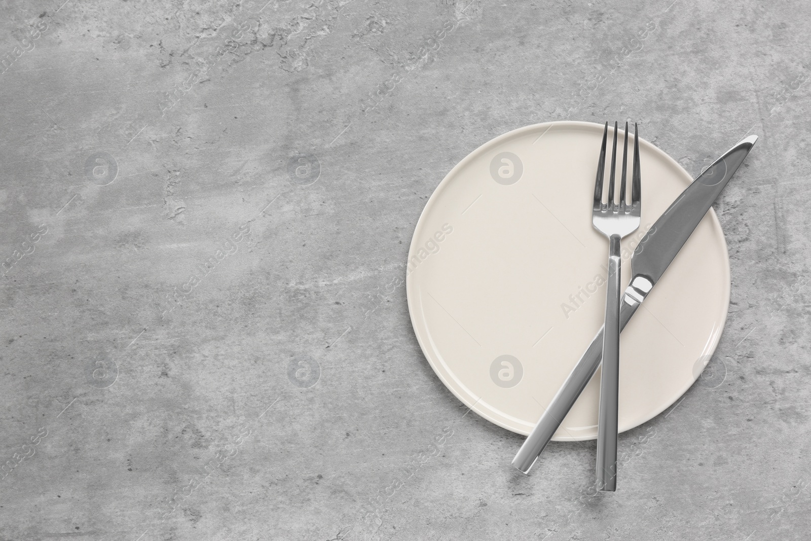 Photo of Clean plate with cutlery on light grey table, flat lay. Space for text