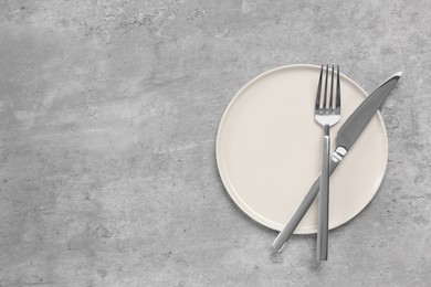Photo of Clean plate with cutlery on light grey table, flat lay. Space for text