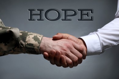 Image of Concept of hope. Soldier and man shaking hands against grey background, closeup