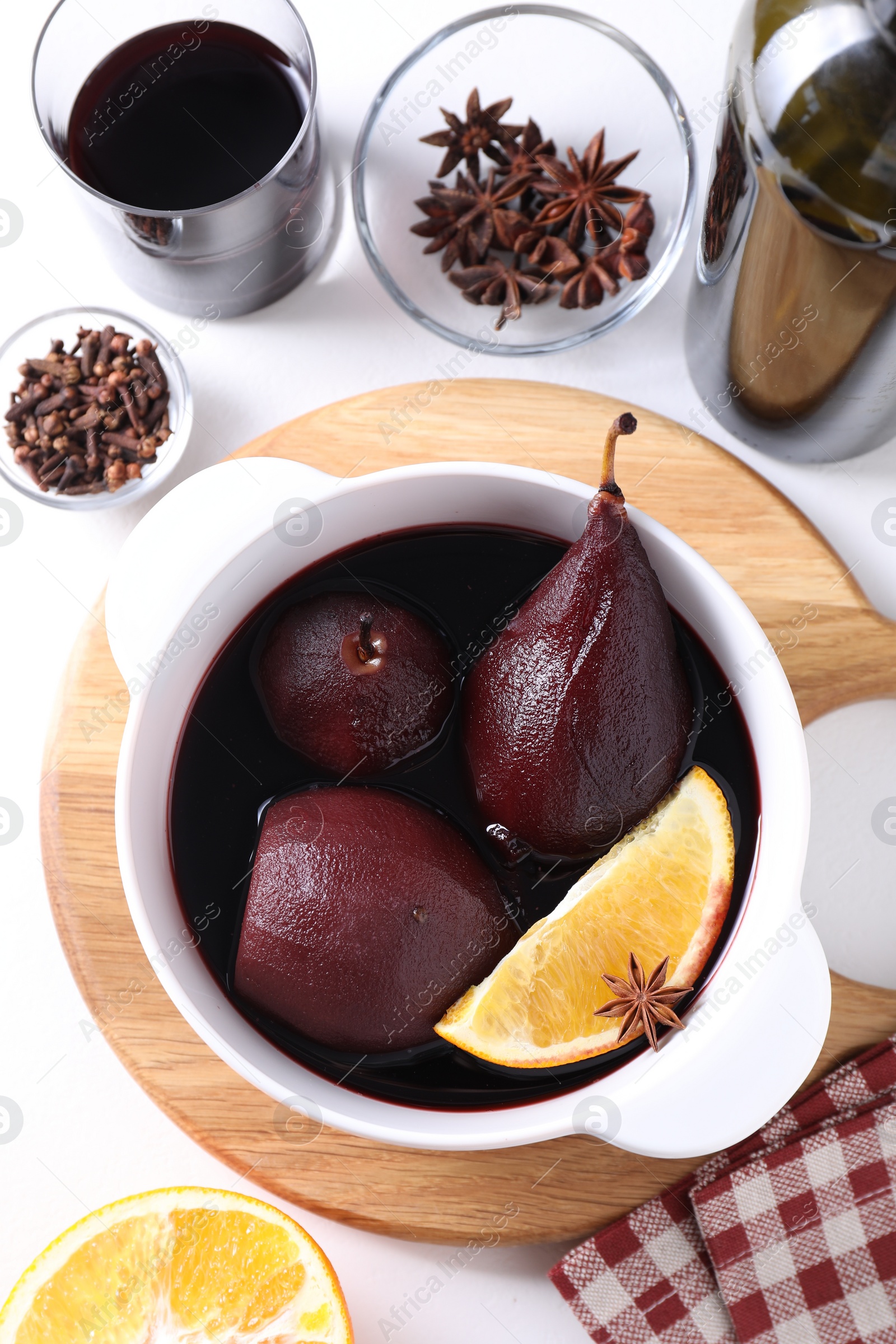 Photo of Tasty red wine poached pears in pot, orange and spices on white table, flat lay