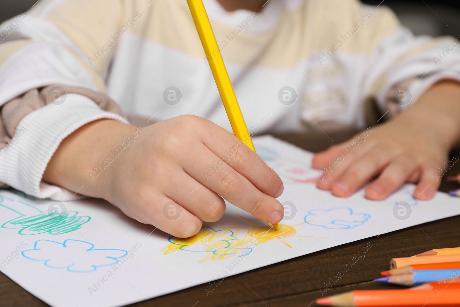 Photo of Little boy drawing with pencil at wooden table, closeup. Child`s art