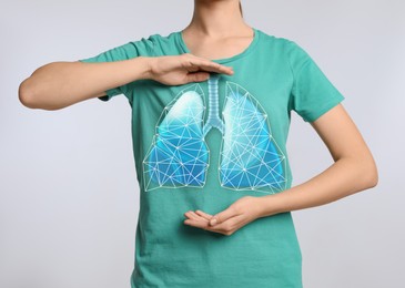 Woman holding hands near chest with illustration of lungs on light grey background, closeup