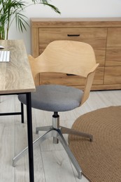 Photo of Stylish office interior with comfortable chair, desk and houseplant