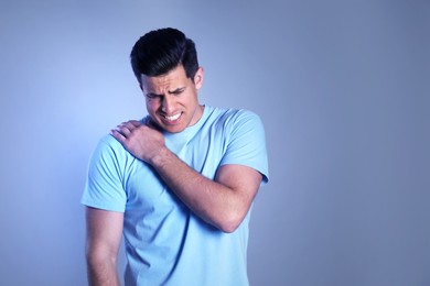 Man suffering from shoulder pain on color background 