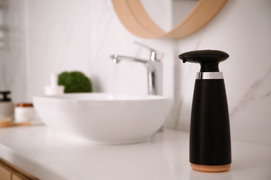 Photo of Modern automatic soap dispenser on countertop in bathroom