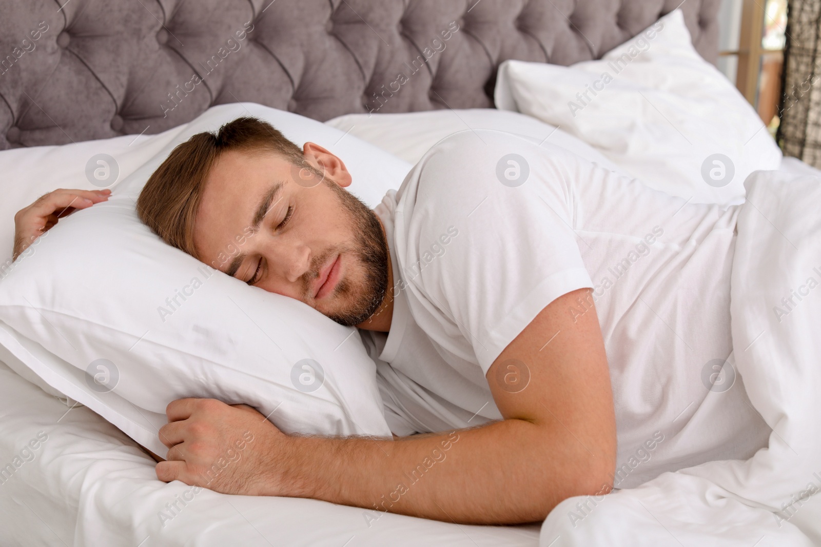 Photo of Young handsome man sleeping in bed at home. Early morning