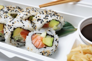 Photo of Food delivery. Delicious sushi rolls in plastic container, closeup