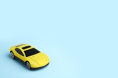 Photo of One yellow car on light blue background, space for text. Children`s toy