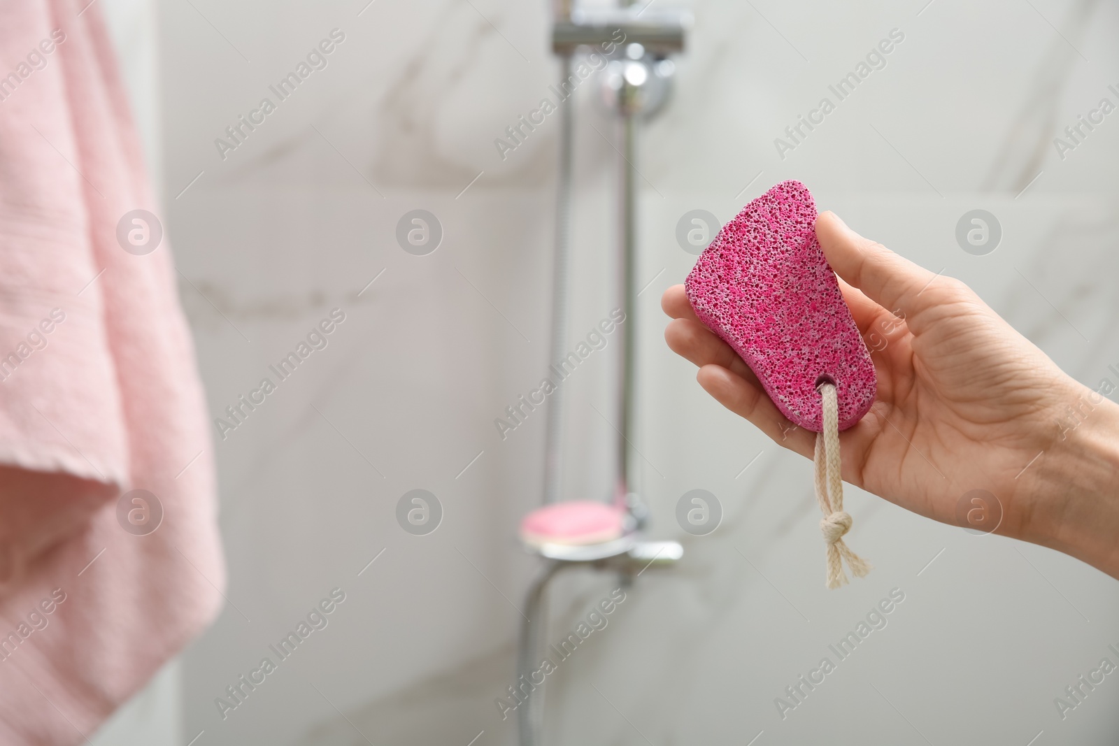 Photo of Woman holding pink pumice stone in shower at home, closeup. Space for text