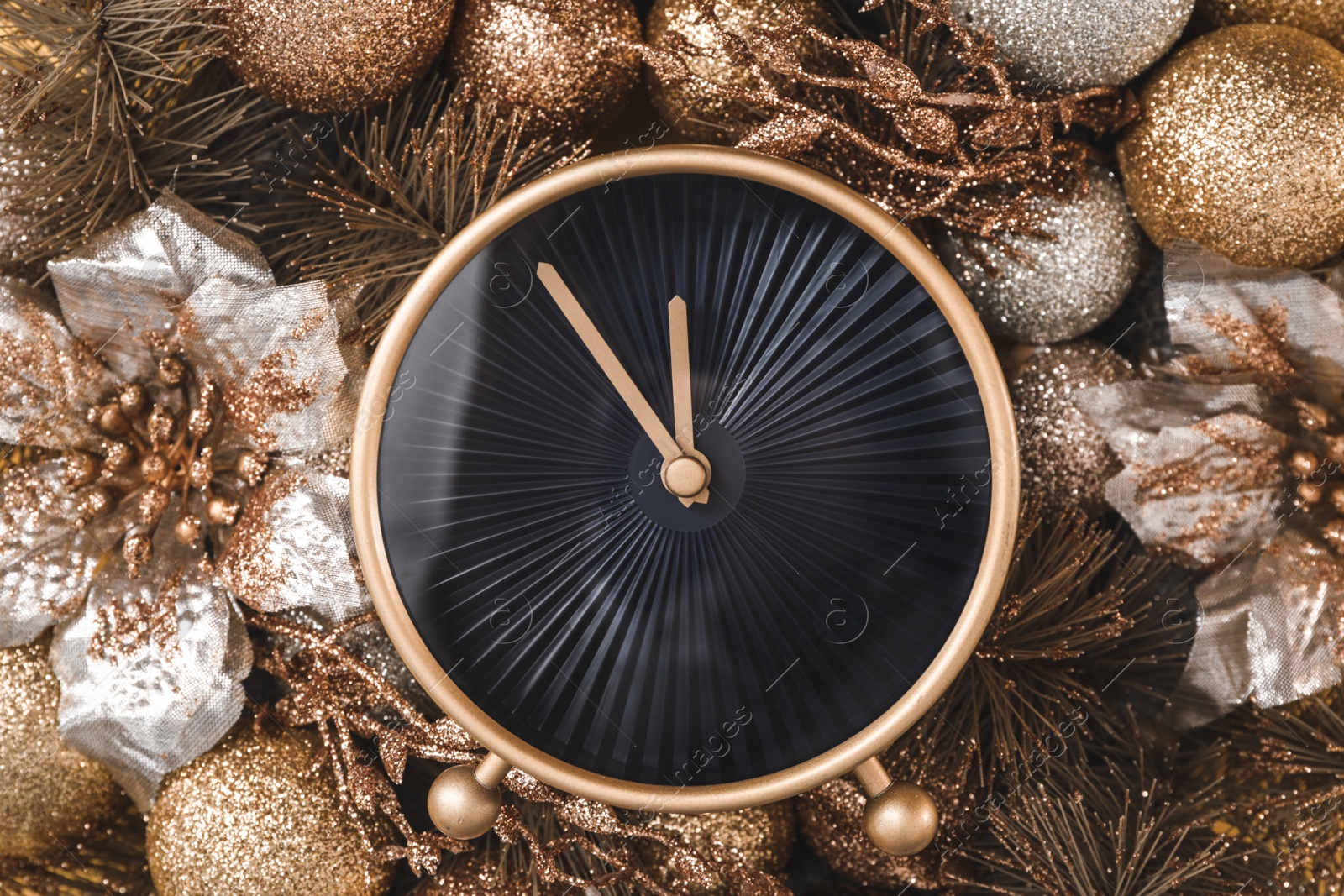 Photo of Alarm clock on golden festive decoration, top view. New Year countdown