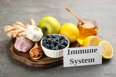 Photo of Card with phrase Immune System and fresh products on grey background