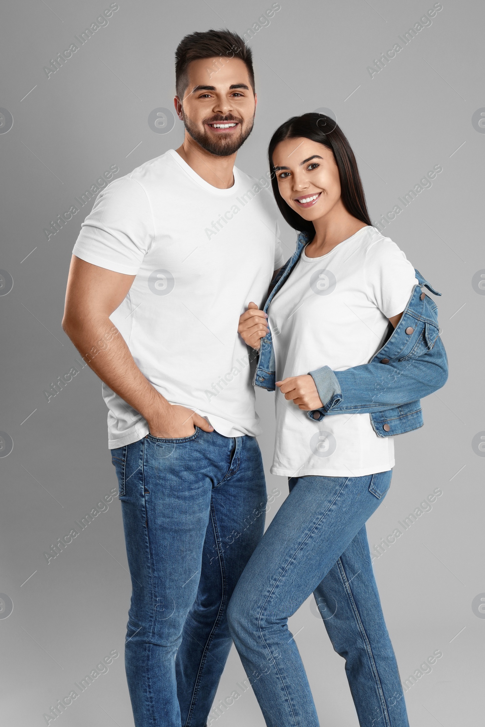 Photo of Young couple in stylish jeans on grey background