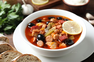 Photo of Meat solyanka soup with sausages, olives and vegetables on table, closeup