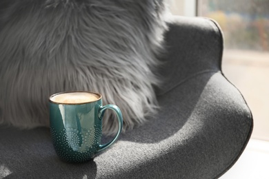 Cup of coffee on armchair indoors