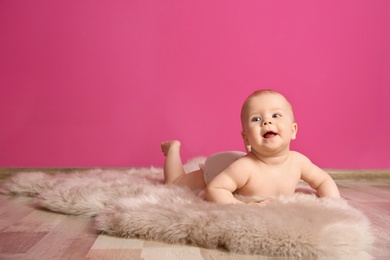 Photo of Cute little baby on fluffy rug near color wall
