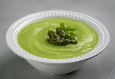 Photo of Delicious asparagus soup on grey table, closeup