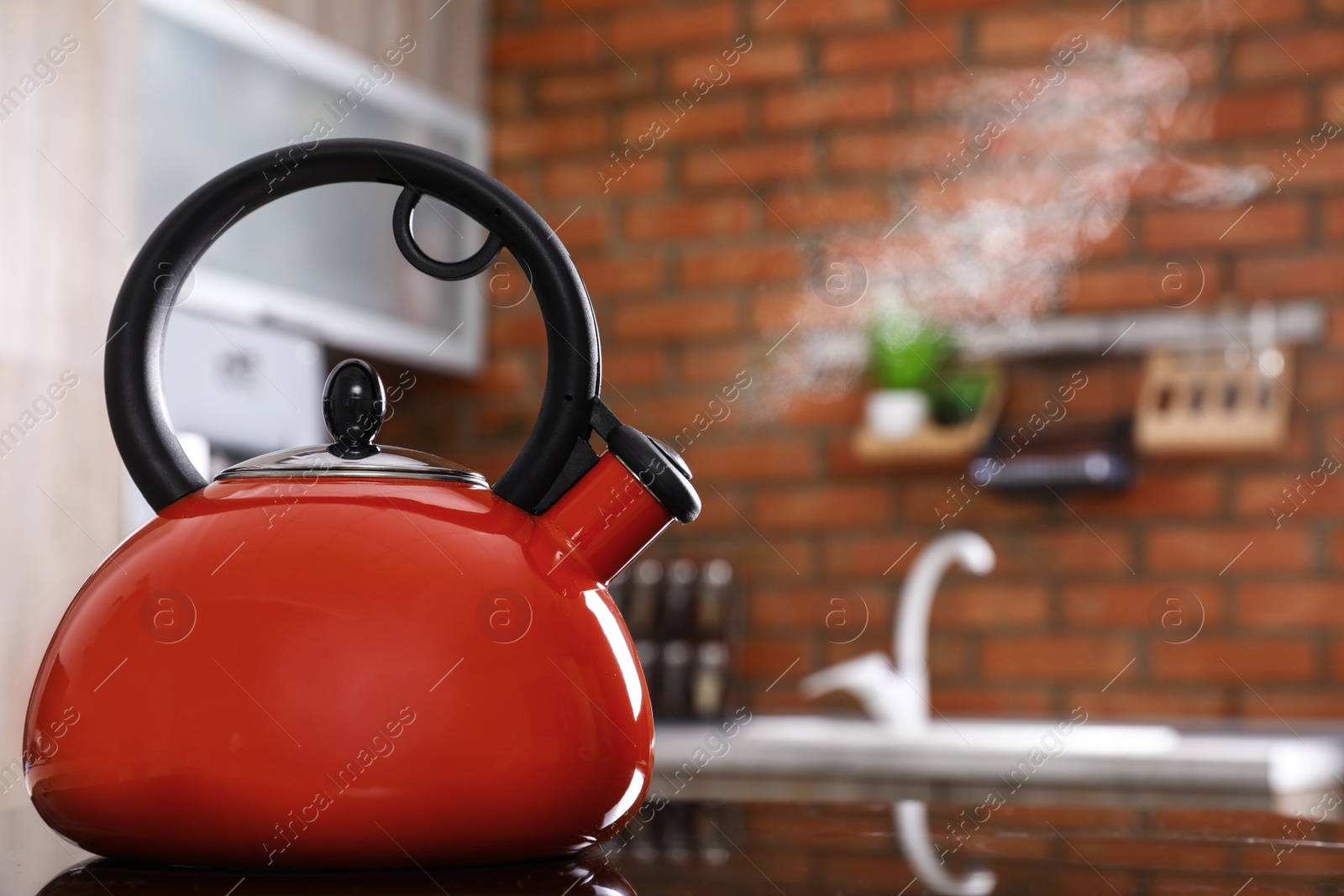 Photo of Modern kettle with whistle on stove in kitchen, space for text