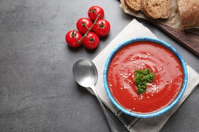 Bowl with fresh homemade tomato soup and space for text on grey background, top view