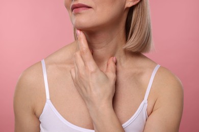 Photo of Woman touching her neck on pink background, closeup