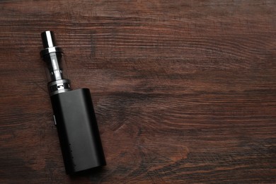 Photo of Electronic cigarette on wooden table, top view with space for text. Smoking alternative