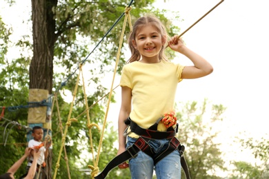 Little girl climbing in adventure park. Summer camp