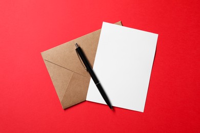 Photo of Blank sheet of paper, letter envelope and pen on red background, top view. Space for text