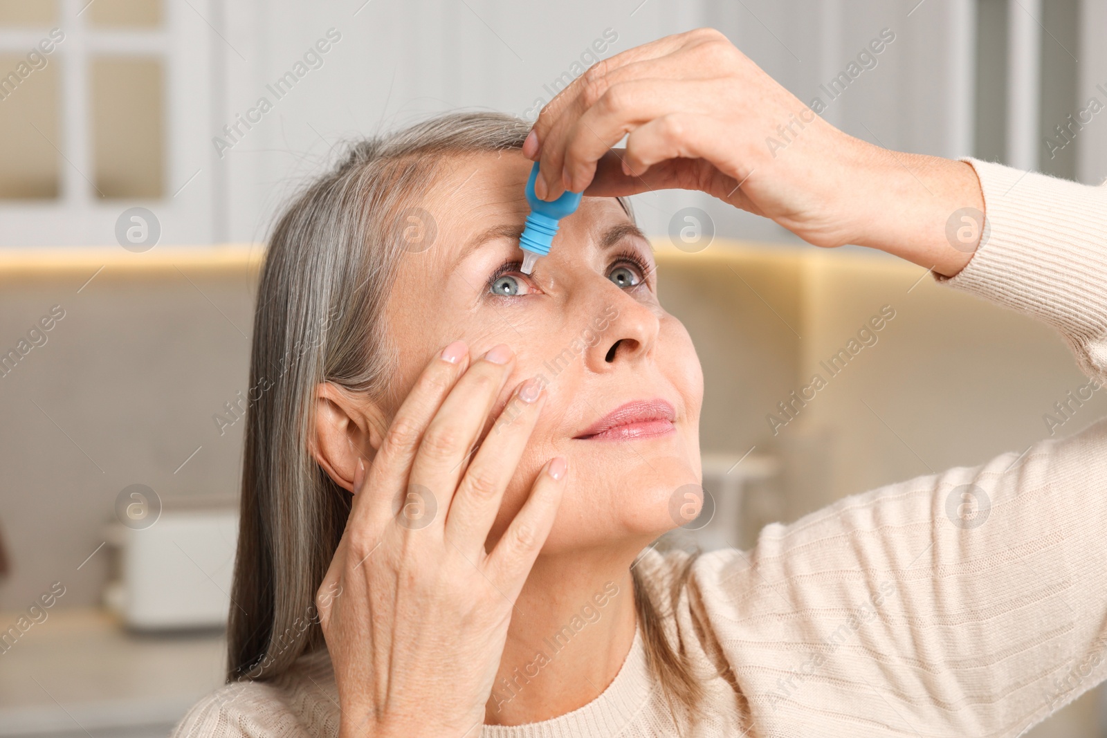 Photo of Woman applying medical eye drops at home