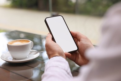 Man using mobile phone at table in outdoor cafe, closeup