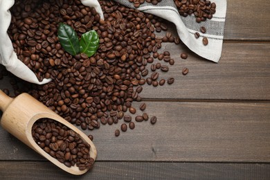 Scoop and bag with roasted coffee beans on wooden table, flat lay. Space for text