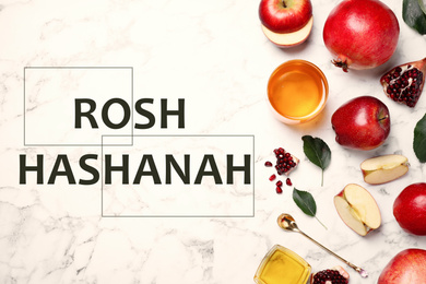 Honey, apples and pomegranates on white marble table, flat lay. Rosh Hashanah holiday