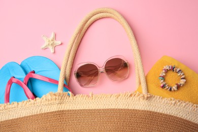 Photo of Bag with beach accessories on pink background, flat lay