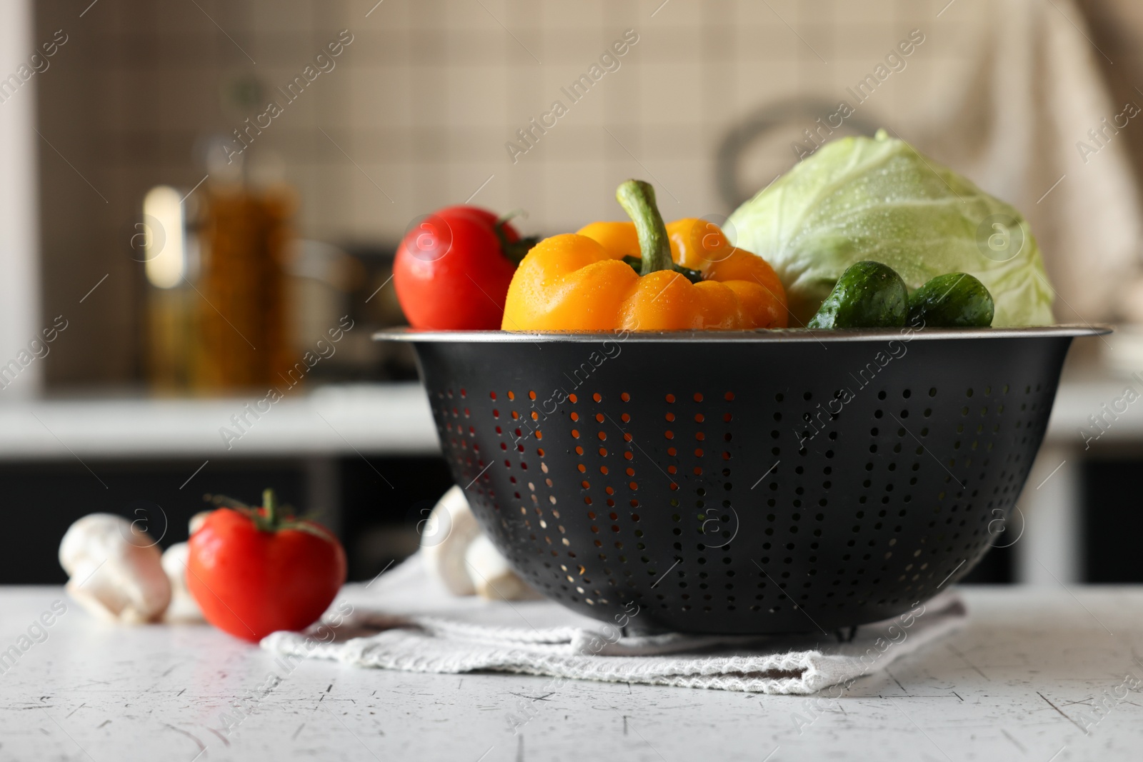 Photo of Metal colander with different wet vegetables on white textured table