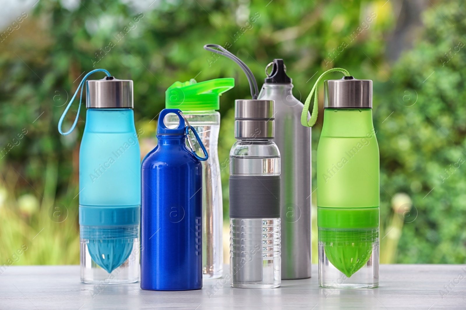 Photo of Sports water bottles on table against blurred background