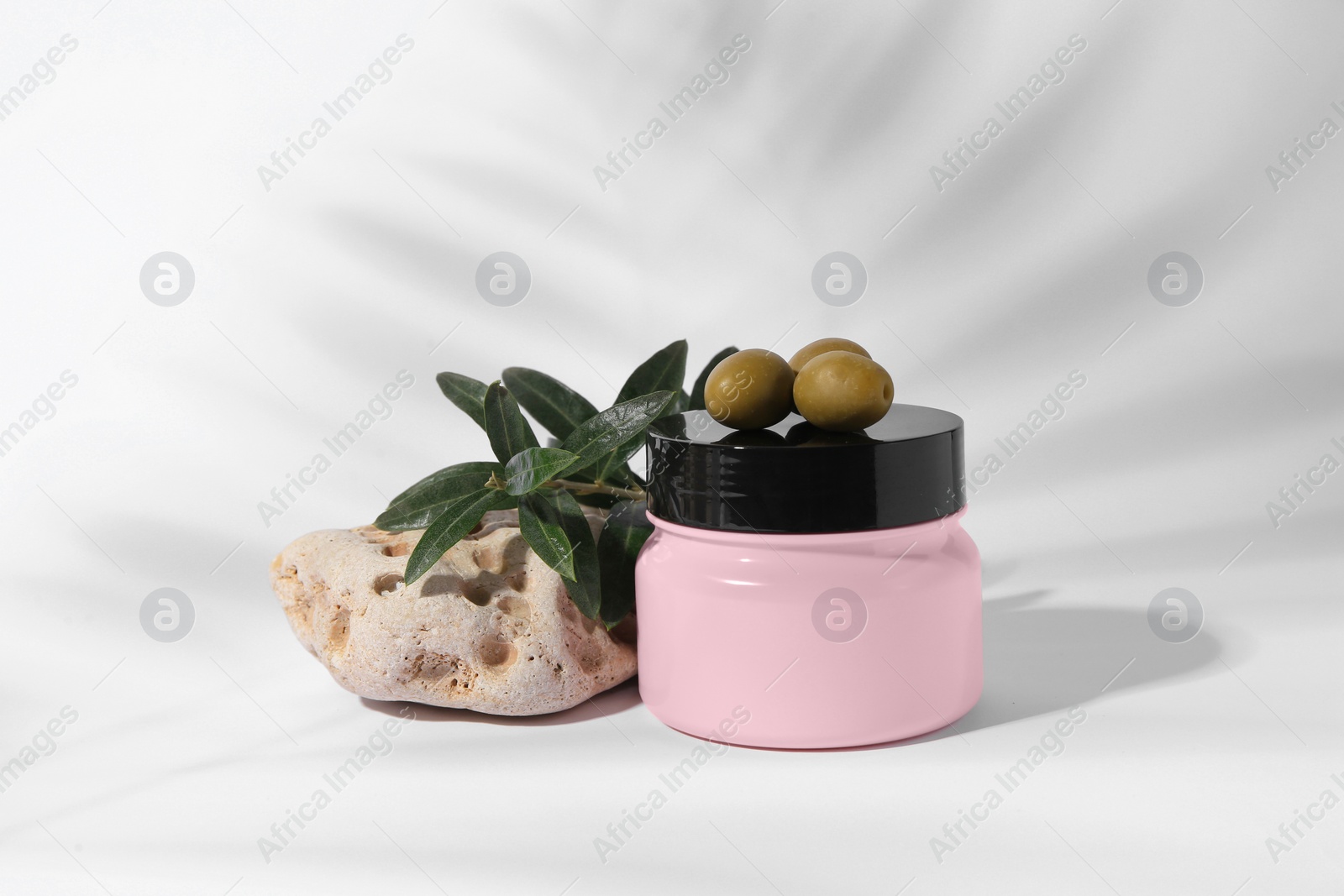 Photo of Jar of natural cream, stone and olives on white background. Cosmetic products