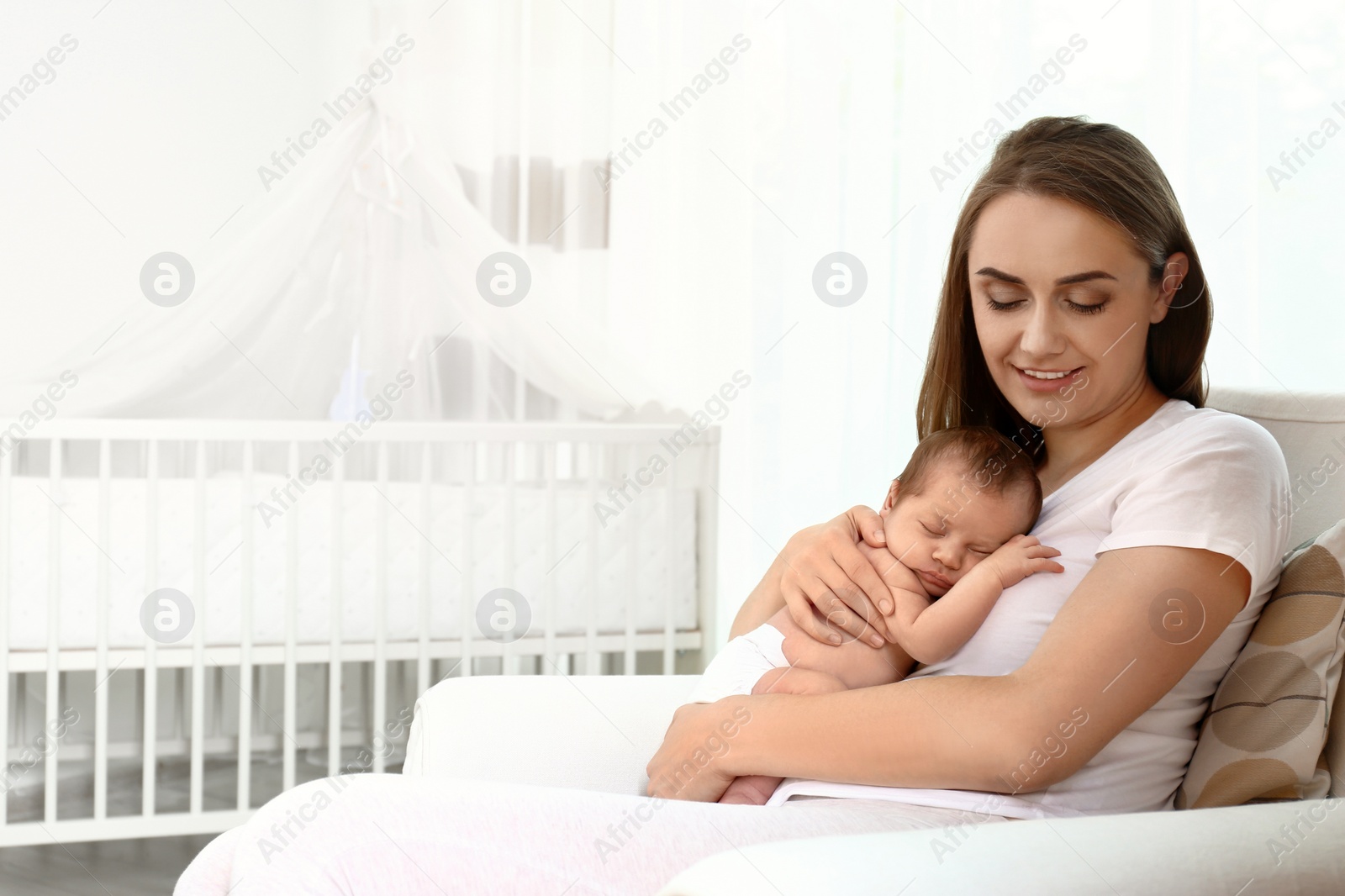 Photo of Young mother with her little baby sitting in armchair at home. Space for text