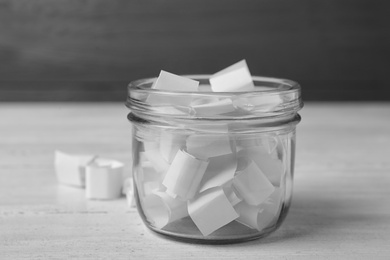 Photo of Glass jar with paper pieces on white wooden table