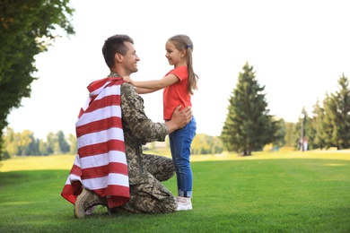 Photo of Father in military uniform with American flag and his daughter at sunny park