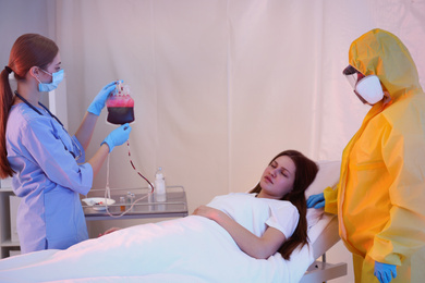 Professional paramedics examining patient with virus in quarantine ward