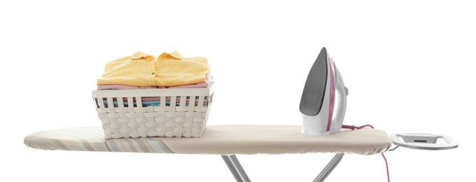 Photo of Board with modern iron and laundry basket on white background