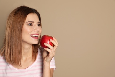 Photo of Smiling woman with perfect teeth and red apple on color background. Space for text