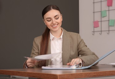 Businesswoman putting document into file folder at wooden table in office