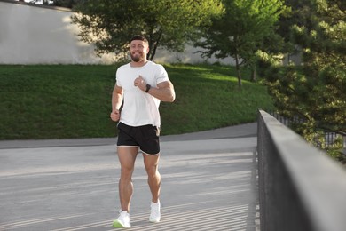 Photo of Smiling man running outdoors on sunny day