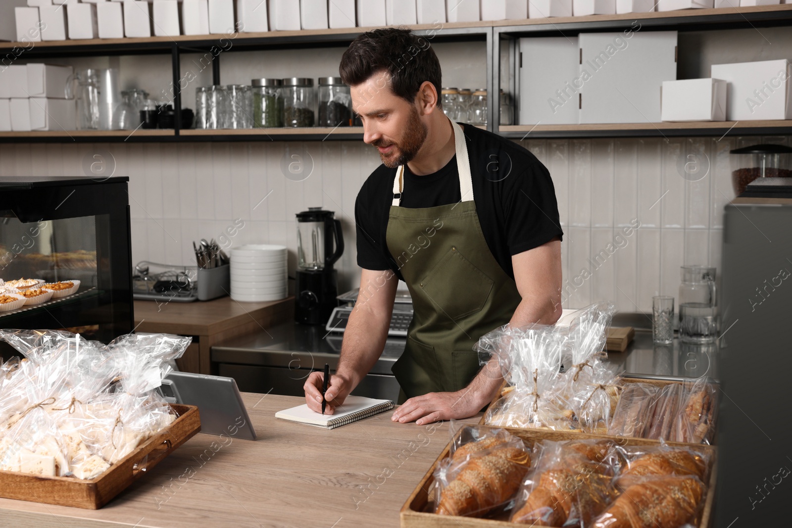 Photo of Seller writing something at cashier desk in bakery shop