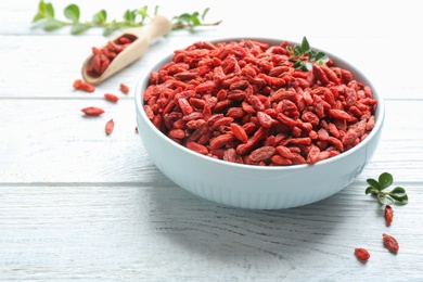 Photo of Bowl of dried goji berries on white wooden table. Healthy superfood
