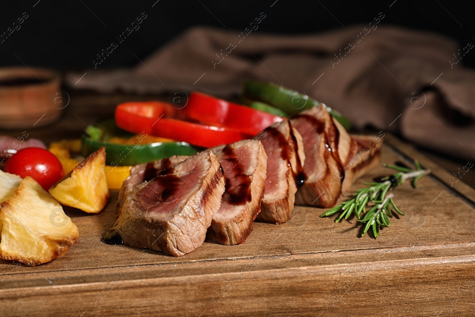 Photo of Cut roasted meat served with sauce and garnish on wooden board, closeup