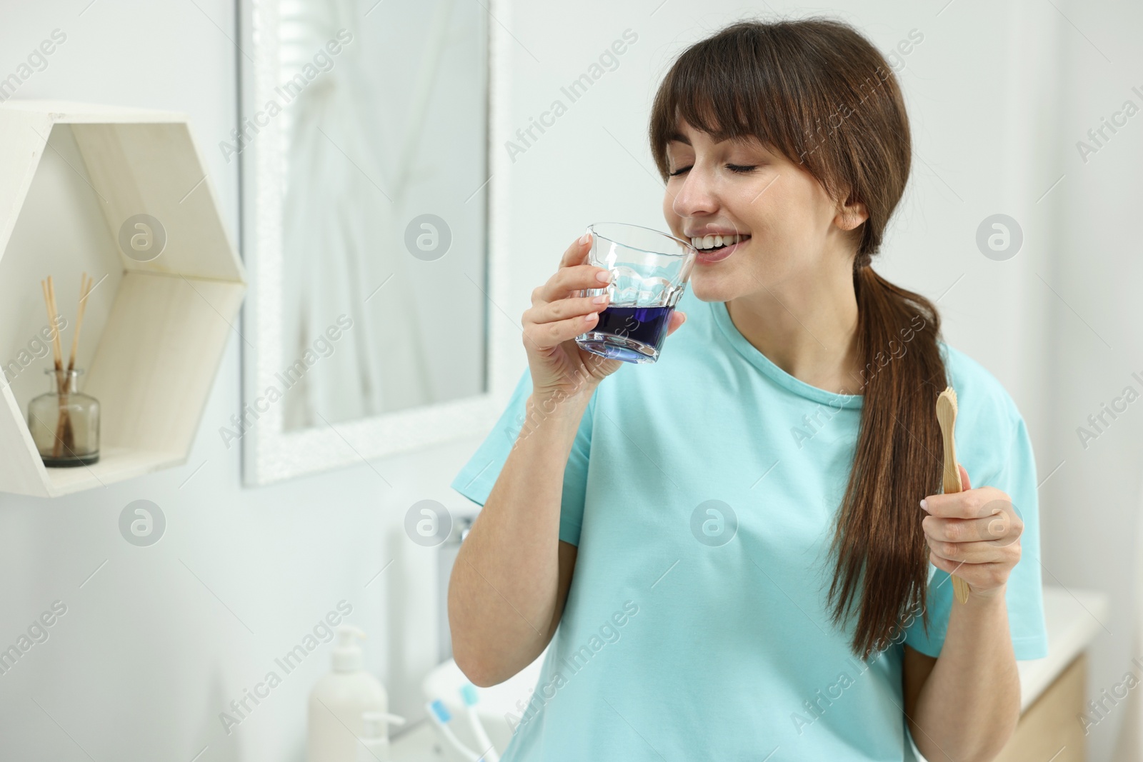 Photo of Young woman using mouthwash in bathroom. Oral hygiene