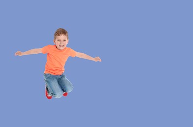 Happy boy jumping on light blue background, space for text