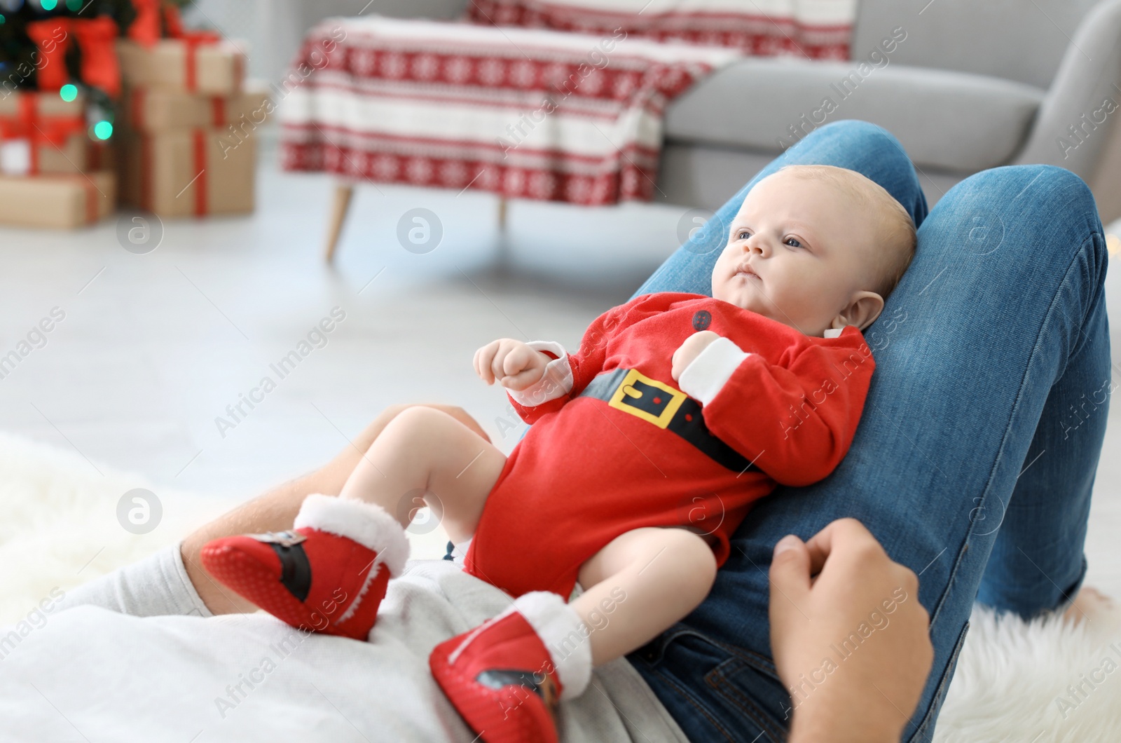 Photo of Young man with baby in Christmas suit at home