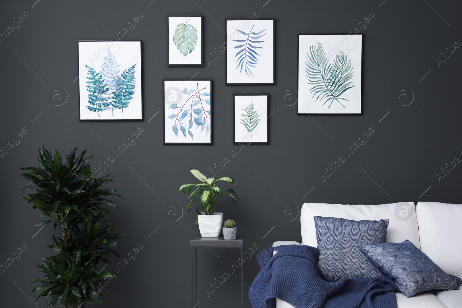 Photo of Beautiful paintings of leaves on black wall in living room interior